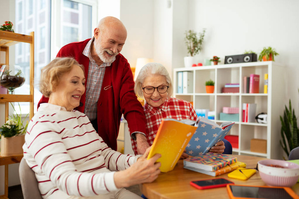 Joyful senior women showing books to their friend - Foto, Bild
