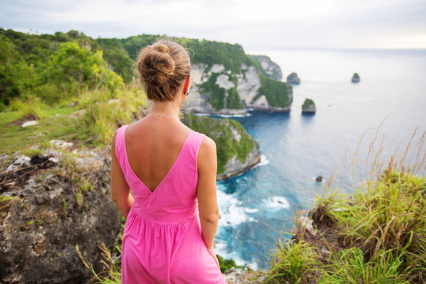  woman sitting on the edge of a cliff and looking at sunset, Nus - Foto, Imagen