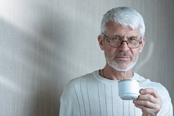 portrait of gray-haired man holding a Cup of coffee - Foto, Imagem