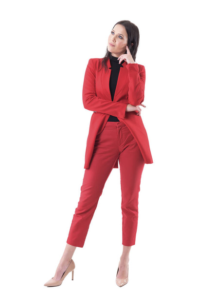 Elegancka młoda kobieta korporacyjna w czerwonym garniturze szuka pomysłu. Pełne ciało izolowane na białym tle. - Zdjęcie, obraz
