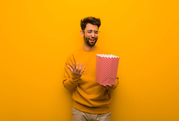 Mladík držící popcorny velmi vyděšený a vystrašený - Fotografie, Obrázek