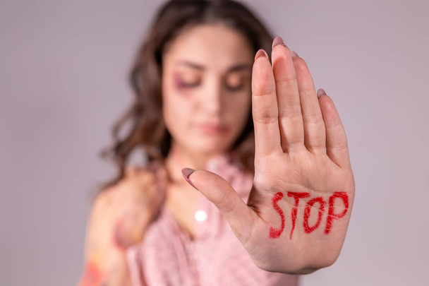 Huiselijk geweld, protesteren en mensen concept - brunette vrouw uiting van ontkenning met Stop op haar hand op grijze kamer - Foto, afbeelding