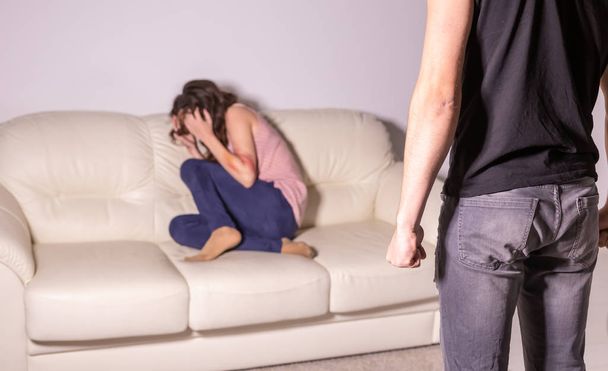 Konzept für häusliche Gewalt und Missbrauch - Mann bedroht weinende Frau mit Faust - Foto, Bild