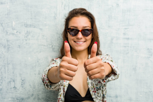 Young european woman wearing bikini with thumbs ups, cheers about something, support and respect concept. - Photo, Image