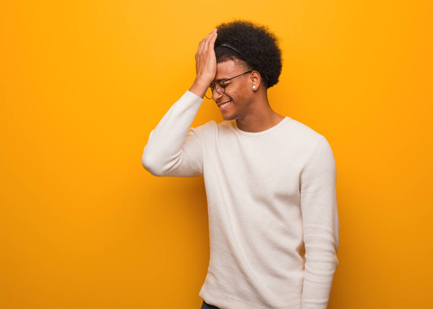 junger afrikanisch-amerikanischer Mann über orangefarbener Wand vergesslich, merke etwas - Foto, Bild