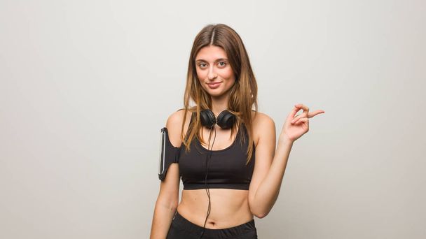 Young fitness russian woman smiling and pointing to the side - Φωτογραφία, εικόνα
