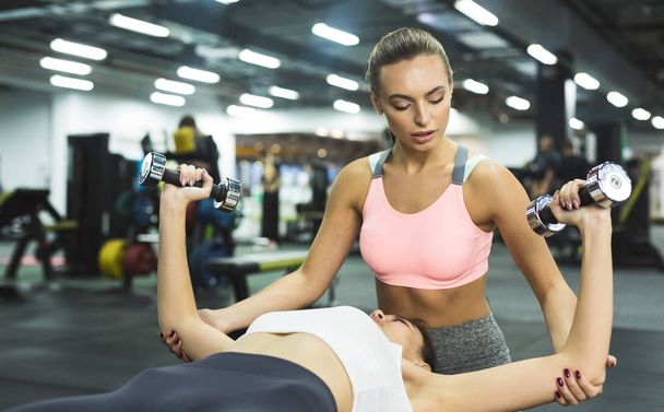 Entraîneur aidant femme à la salle de gym, donnant haltérophilie entraînement
 - Photo, image