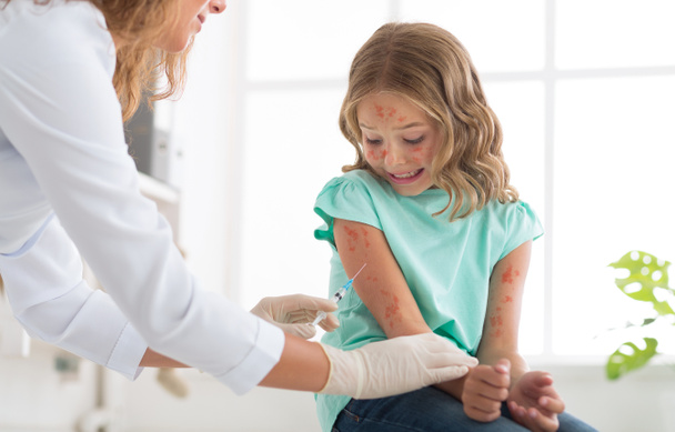 Vacunación antisarampión. Médico inyectando vacuna a niña
 - Foto, imagen