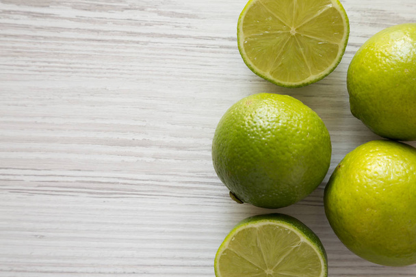 Green citrus limes on a white wooden background, top view. From  - Photo, image