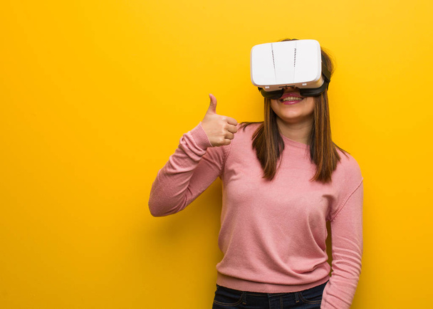 Young cute woman wearing a virtual reality googles smiling and raising thumb up - Photo, Image