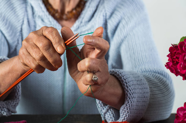 Öreg hölgy ráncos kézzel nem kötés. Hobbi és kézzel tenni az emberek nyugdíjba. Mesterkurzus kézműves és kötés. Öregedési folyamat és az idősek. Kézzel készített ruhák - Fotó, kép
