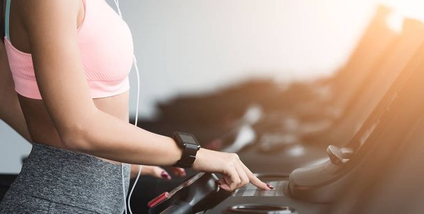 Adjusting speed. Woman training on treadmill in gym - Foto, immagini