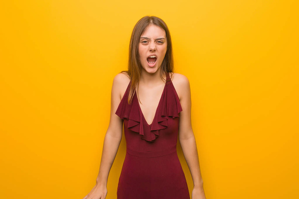 jonge elegante vrouw het dragen van een jurk schreeuwen zeer boos en agressief - Foto, afbeelding