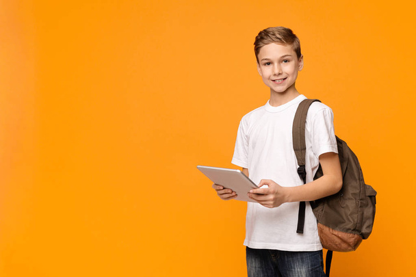 Schoolboy z plecaka za pomocą komputera typu tablet i uśmiechnięty - Zdjęcie, obraz