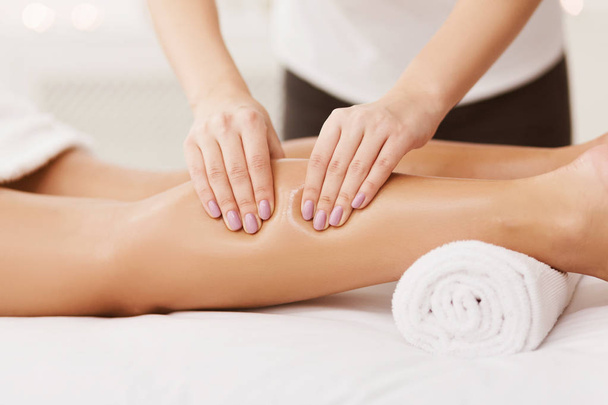 Massage therapeut masseren vrouw kalveren in spa centrum - Foto, afbeelding