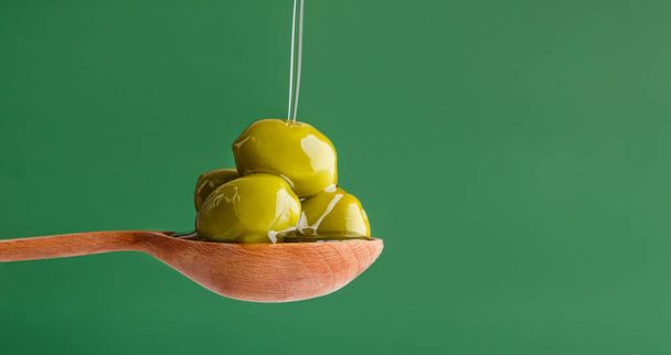 Vihreät oliivit lusikassa vihreällä
 - Valokuva, kuva