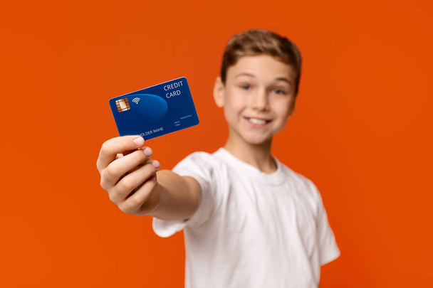 Sonriente chico mostrando tarjeta de crédito en la cámara
 - Foto, imagen