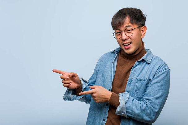 Nuori kiinalainen mies osoittaa sivulle sormella
 - Valokuva, kuva