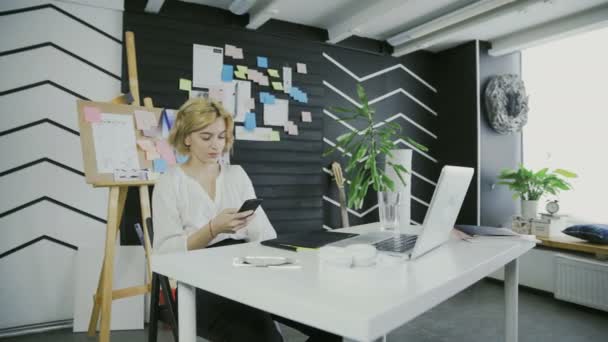 Mladá žena pomocí aplikace na smartphone v kanceláři - Záběry, video