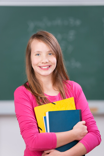 Schoolgirl smiling and holding her notebooks - Fotoğraf, Görsel