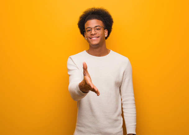 Молодий афроамериканець через оранжеву стіну, щоб привітати когось - Фото, зображення