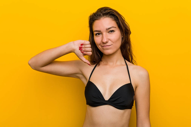 Mujer europea joven con bikini mostrando un gesto de aversión, pulgares hacia abajo. Concepto de desacuerdo
. - Foto, Imagen