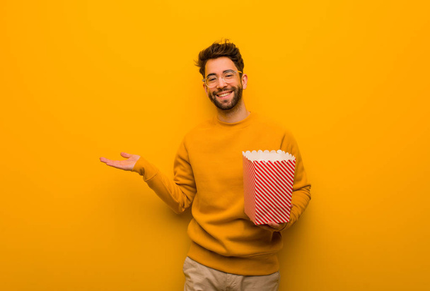 Giovane uomo che tiene popcorn che tiene qualcosa con mano
 - Foto, immagini