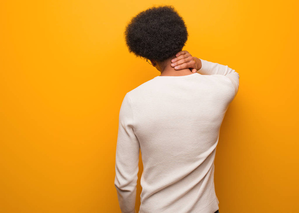 Νεαρός Αφροαμερικάνος πάνω από έναν πορτοκαλί τοίχο από πίσω σκέφτεται κάτι - Φωτογραφία, εικόνα