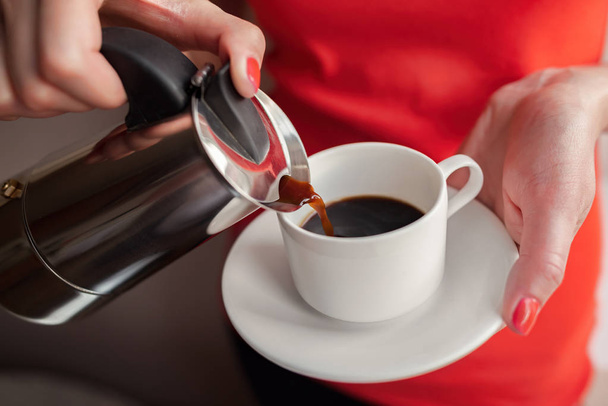 Nainen kaataa kahvia kuppiin kahvinkeittimestä.
. - Valokuva, kuva