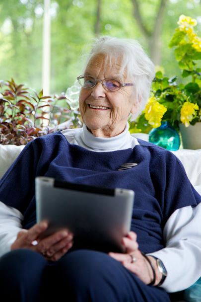 Mutlu yaşlı kadın tablet kullanıyor ve gülüyor. - Fotoğraf, Görsel