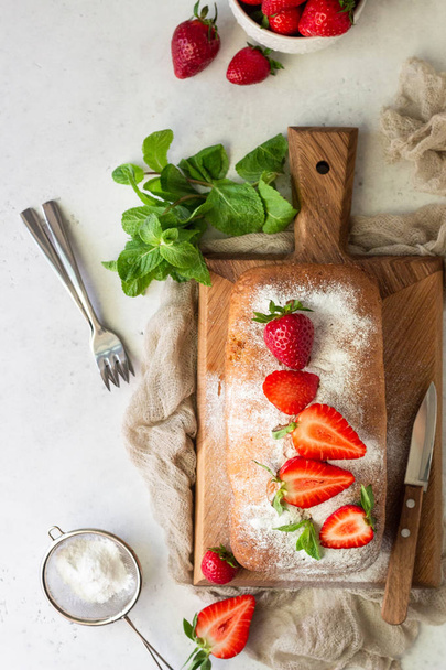 Pound or loaf cake with strawberry and mint on wooden board. Delicious summer dessert. - Photo, Image