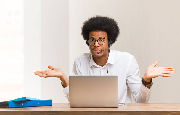 Fiatal telemarketinges fekete férfi zavaros és kétes - Fotó, kép