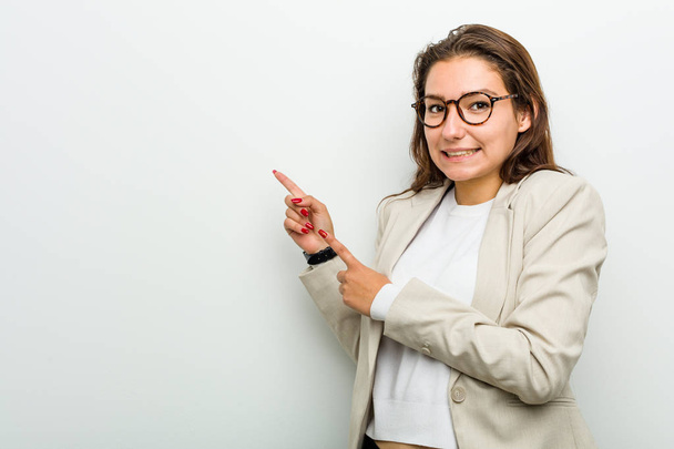 Молодая европейская деловая женщина шокирована, указывая указательными пальцами на пространство для копирования
. - Фото, изображение