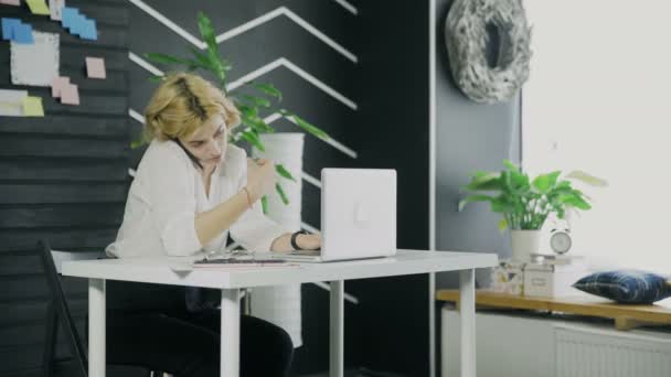 Молода бізнес-леді говорить на своєму смартфоні під час роботи на ноутбуці
 - Кадри, відео