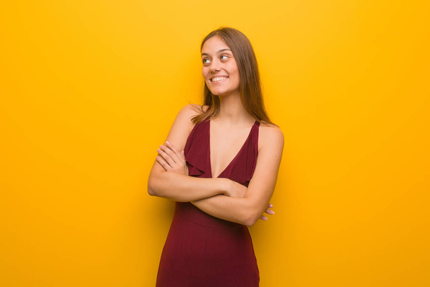 Young elegant woman wearing a dress smiling confident and crossing arms, looking up - Foto, imagen