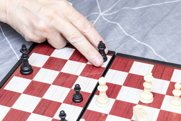 Hand of an elderly senior woman playing chess close up, entertainment and intellectual activity for retired people concept - Photo, image