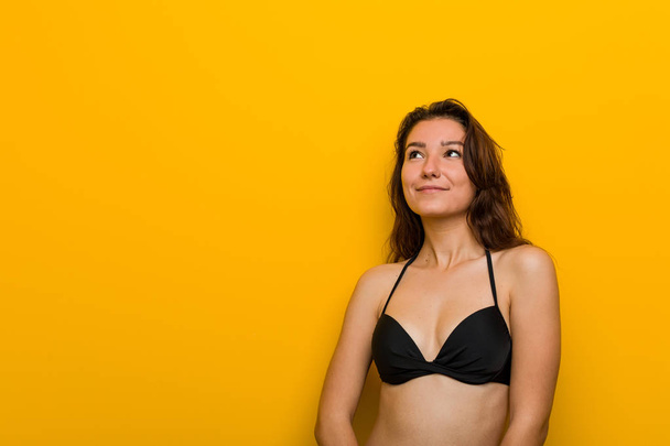 Young european woman wearing bikini dreaming of achieving goals and purposes - Foto, imagen