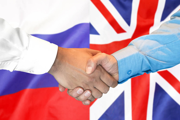 χειραψία στο Ηνωμένο Βασίλειο και τη Ρωσία σημαία φόντο. - Φωτογραφία, εικόνα