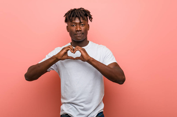 Молодий африканський чорний чоловік посміхається і показує форму серця з його руками
. - Фото, зображення