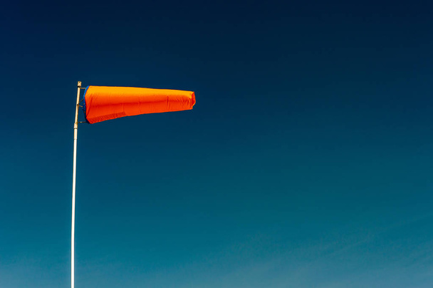 Yatay uçan turuncu windsock ve açık lacivert gökyüzü. - Fotoğraf, Görsel
