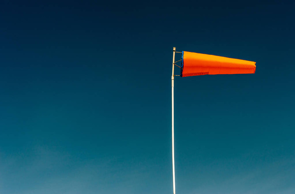 horizontal fliegende orangefarbene Windsack und klarer dunkelblauer Himmel. - Foto, Bild