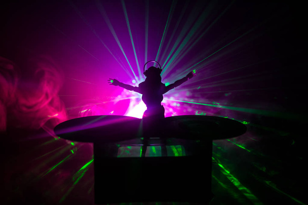 Concepto de club de DJ. Mujer mezclando DJ, y rascándose en un club nocturno. Silueta de niña en la cubierta de DJ, luces estroboscópicas y niebla en el fondo. Decoración creativa de obras de arte con juguete
. - Foto, imagen