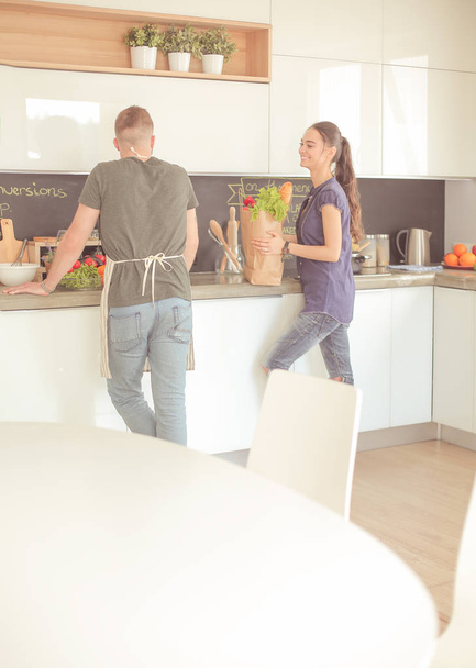 Beautiful young couple is having fun in kitchen at home - Fotografie, Obrázek