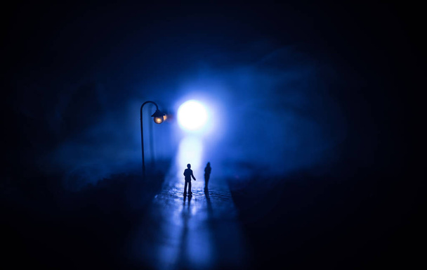 Casal jovem segurando as mãos um do outro. Caminhando lentamente sob luzes brancas de rua durante a noite. Tempo negro. Atmosfera pacífica em névoa. Ar enevoado
. - Foto, Imagem