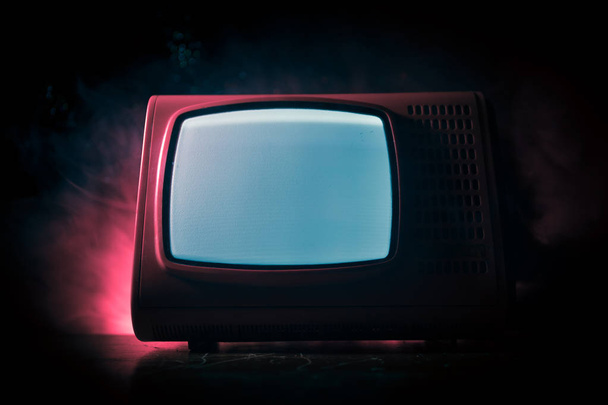Old vintage red TV with white noise on dark toned foggy background. Retro old Television reciever no signal. Selective focus - Photo, Image
