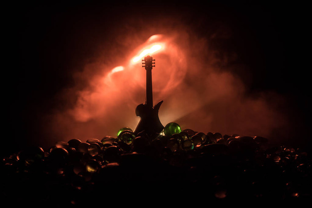 Концепция музыки. Акустическая гитара изолирована на тёмном фоне под лучом света с дымом с копировальным пространством. Гитарные струны, закройте. Выборочный фокус. Пожарные. Сюрреалистичная гитара
 - Фото, изображение