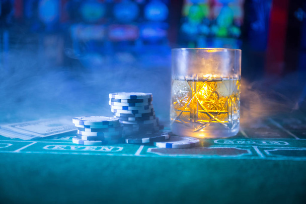 juego, fortuna, juego y concepto de entretenimiento - primer plano de fichas de casino y vaso de whisky en la mesa
 - Foto, imagen