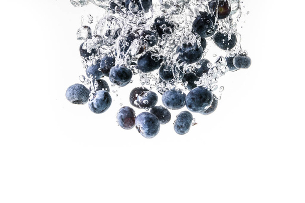Blueberries splashing into crystal water - Photo, Image