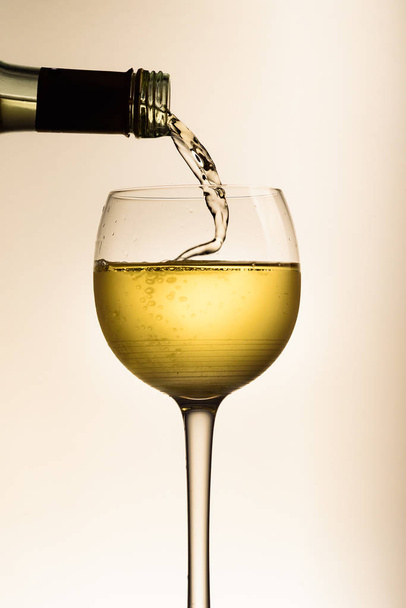 Versare il vino bianco nel bicchiere dalla bottiglia
 - Foto, immagini