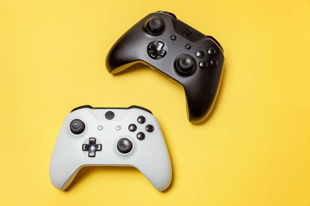 Sarı arka planda beyaz ve siyah iki joystick. Bilgisayar oyun Yarışması videogame kontrol çatışma kavramı - Fotoğraf, Görsel